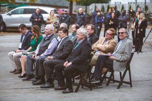 A group of people are sitting in chairs in a parking lot.