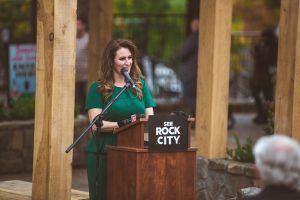 A woman is standing at a podium speaking into a microphone.