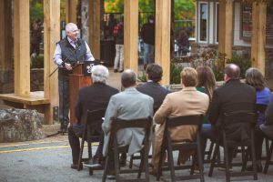 A man is giving a speech to a group of people sitting in chairs.