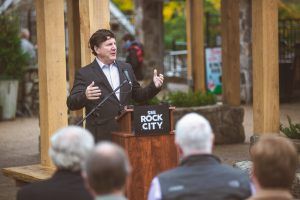 A man is standing at a podium giving a speech to a group of people.
