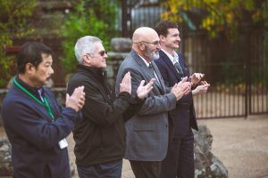 A group of men are standing next to each other clapping their hands.