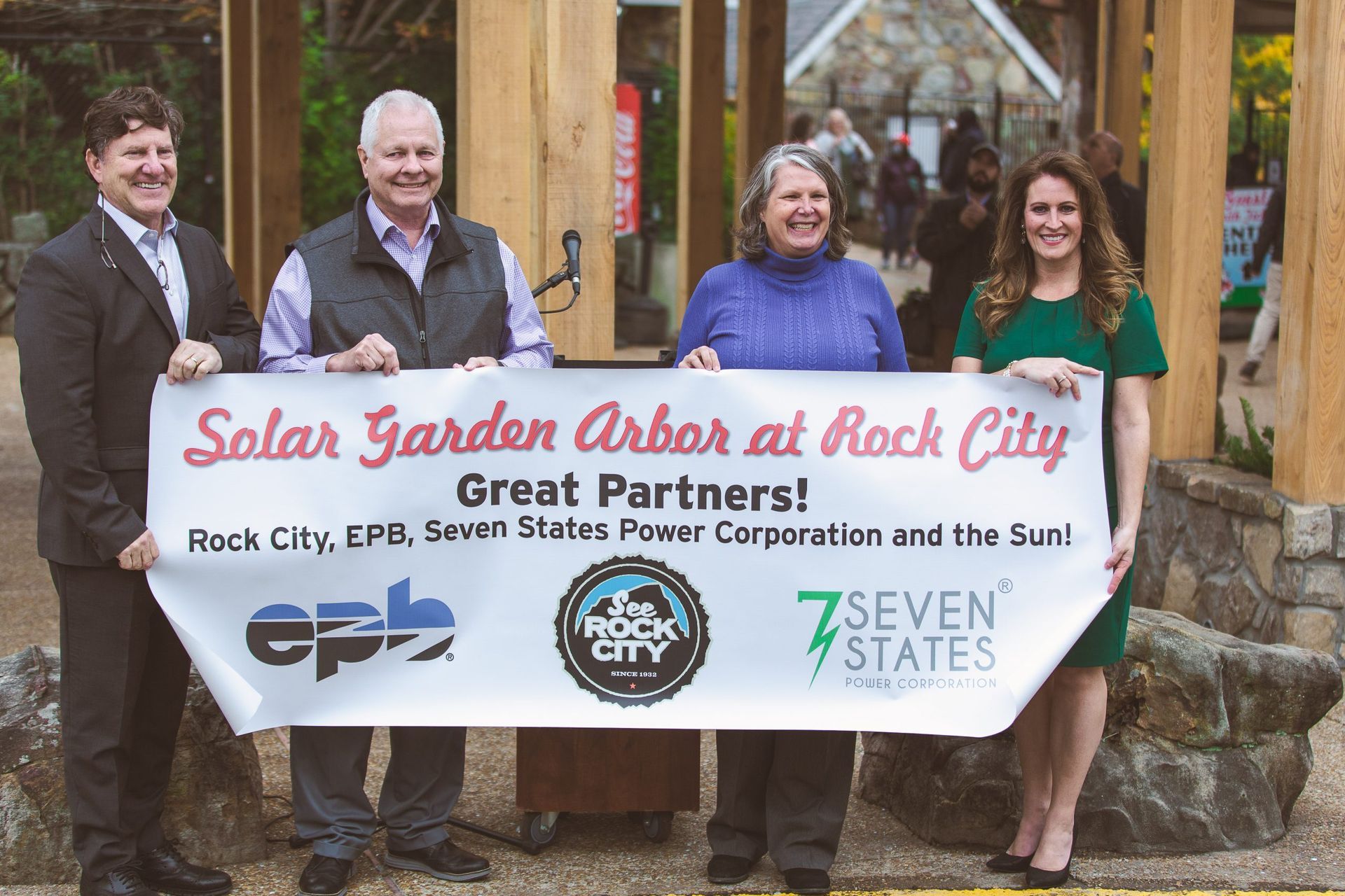 A group of people holding a banner that says solar garden arbor at rock city