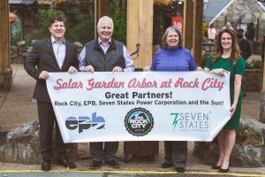 A group of people holding a banner that says solar garden arbor at rock city