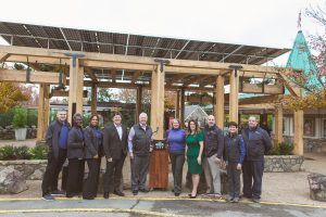 A group of people are standing in front of a building with solar panels on the roof.