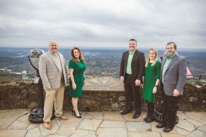 A group of people standing next to each other on top of a hill.