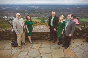 A group of people standing next to each other on top of a hill.