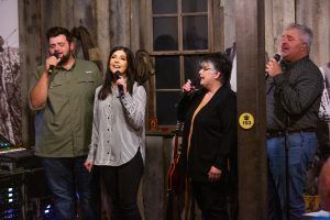 A group of people are singing into microphones in a room.