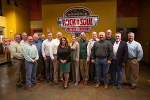 A group of people are posing for a picture in front of a sign that says rock n soul.