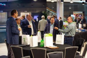 A group of men are standing around a table with bags on it.