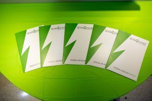 Four green and white business cards with lightning bolts on them are sitting on a green table.