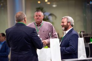 A group of men are shaking hands at a conference.