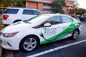 A white and green electric car is parked in a parking lot.