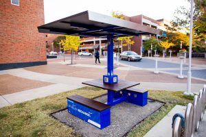 A blue picnic table with a solar panel on top of it.