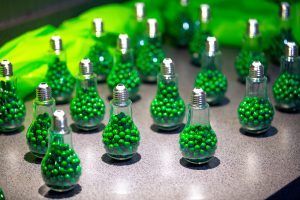A bunch of light bulbs filled with green balls on a table.