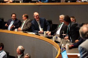 A group of men are sitting at a table in a conference room.