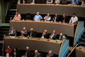 A group of people are sitting at tables in a conference room