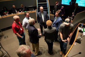 A group of people are standing in a room talking to each other.