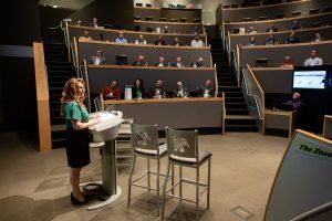 A woman is standing at a podium in front of an empty auditorium.