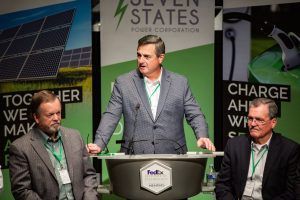 A man is standing at a podium giving a speech to two other men.