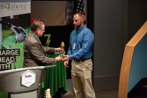 Two men are shaking hands in front of a podium.