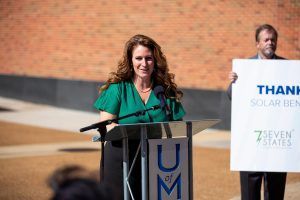 A woman is standing at a podium holding a thank you sign.