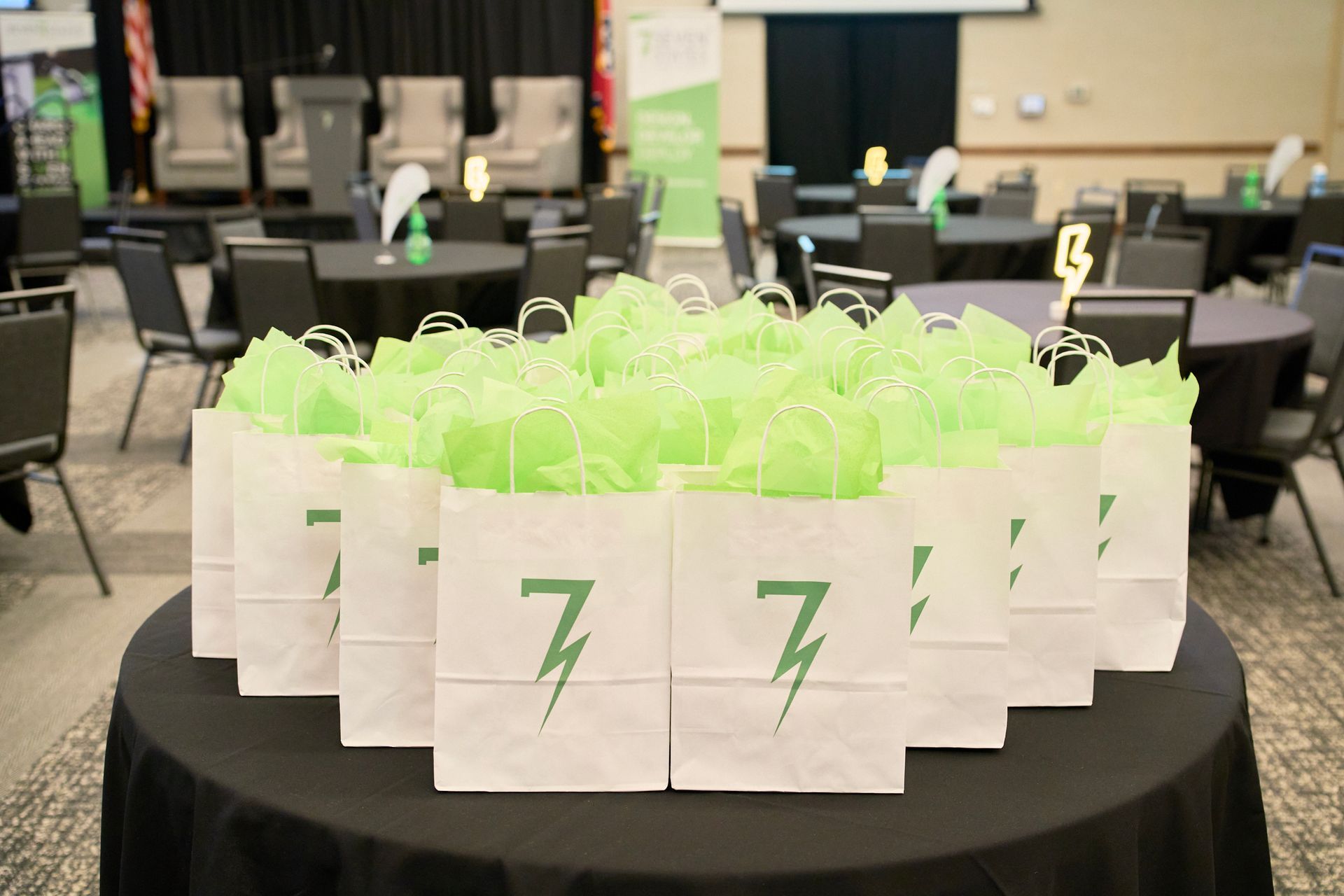 A table topped with a bunch of white bags with green tissue paper and a lightning bolt on them.