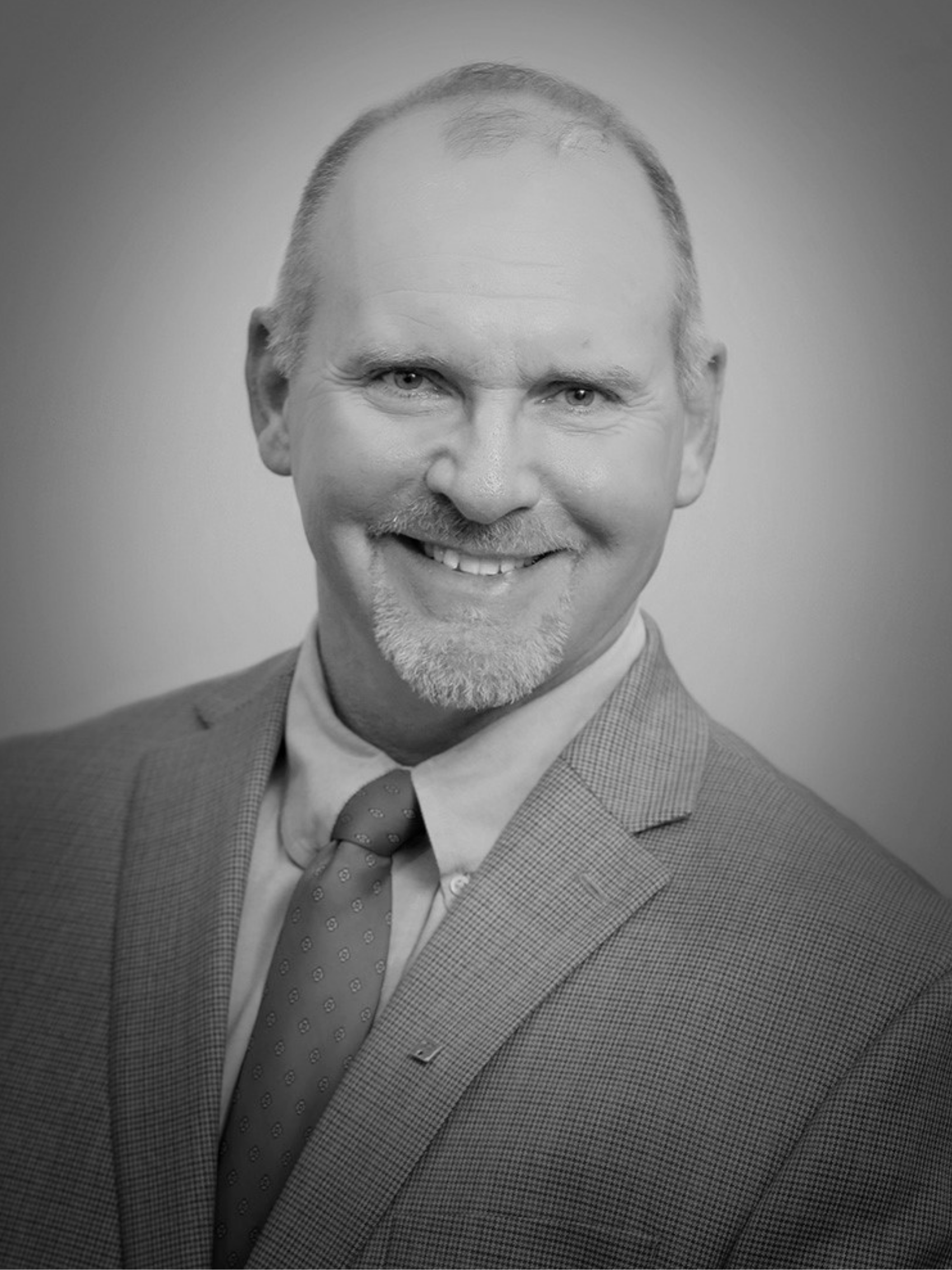 A man in a shirt and tie is smiling in a black and white photo