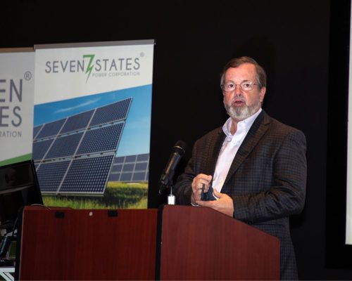 A man stands at a podium in front of a seven states sign