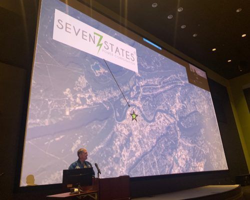A man is giving a presentation in front of a large screen.