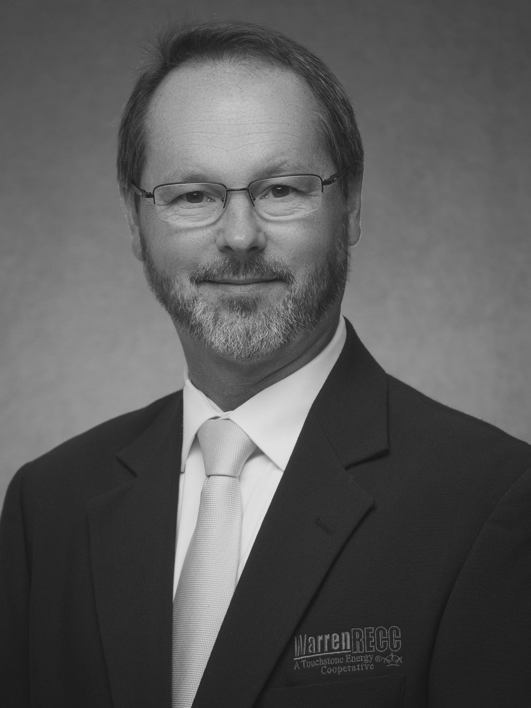 A man in a shirt and tie is smiling in a black and white photo