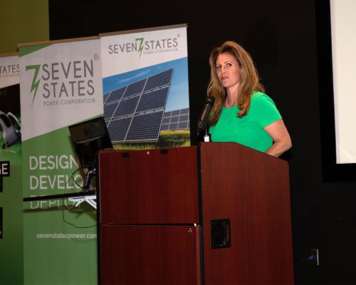 A woman is standing at a podium giving a presentation for seven states