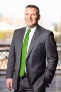 A man in a suit and green tie is standing with his hands in his pockets.