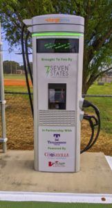 A 7 seven states charging station with a tree in the background.