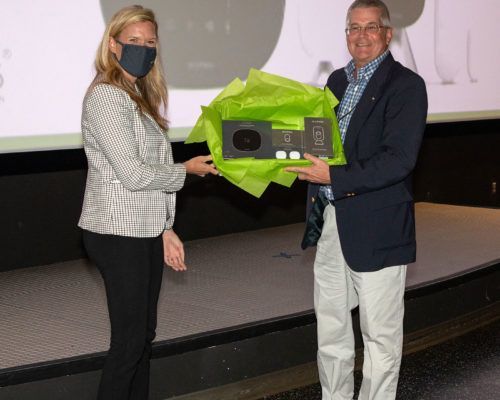 A man is giving a gift to a woman who is wearing a mask.