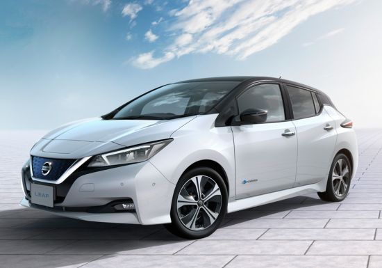 A white nissan leaf is parked on a tiled floor.