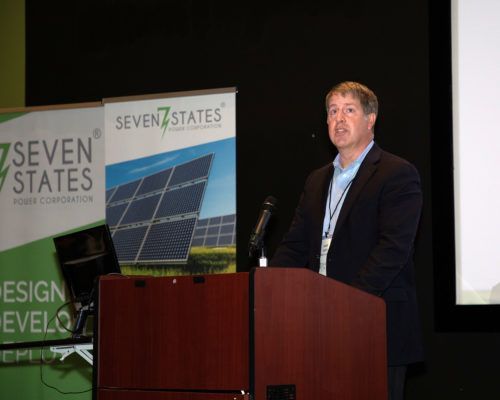 A man in a suit is standing at a podium giving a presentation.