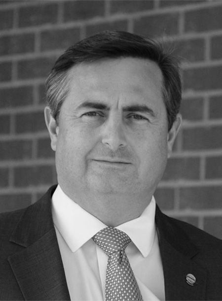 A man in a suit and tie is standing in front of a brick wall.
