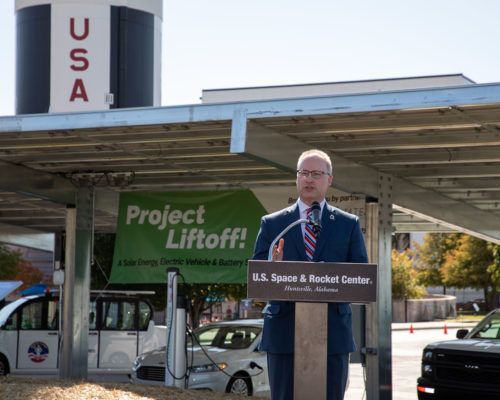 A man stands at a podium in front of a sign that says project liftoff