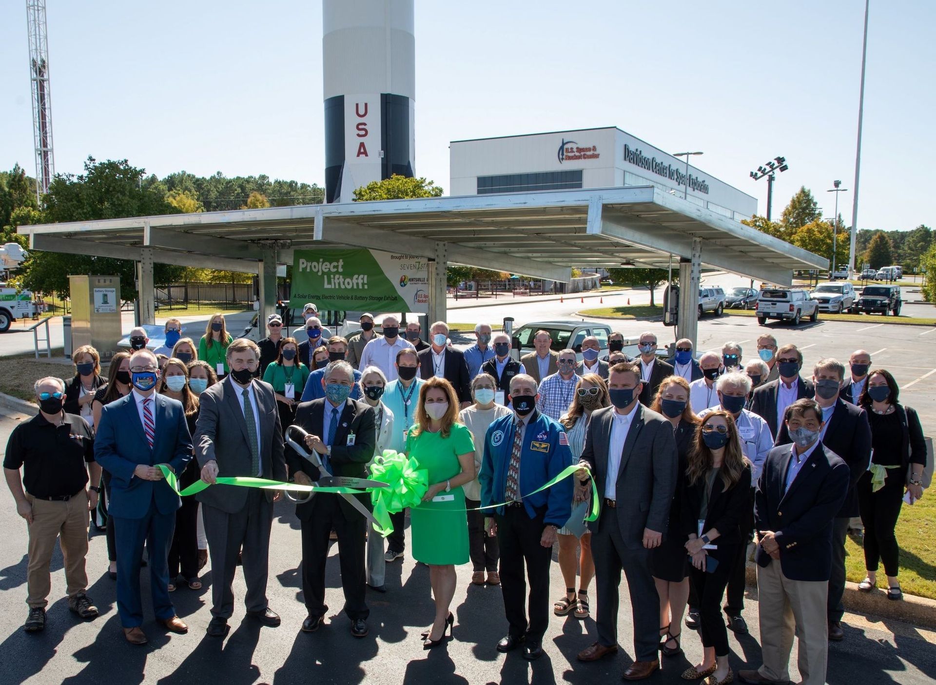 A large group of people are standing in front of a rocket.