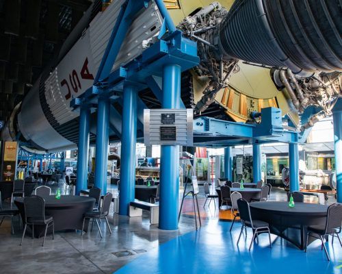 A room with tables and chairs and a rocket in the background