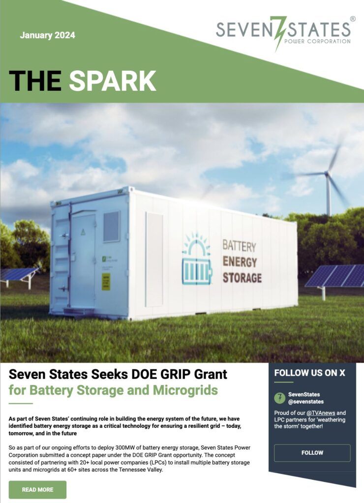 A white shipping container is sitting on top of a lush green field next to solar panels.