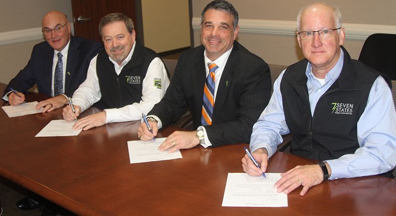 A group of men are sitting at a table signing papers