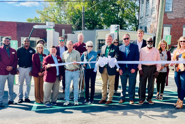 A group of people are standing in front of a ribbon cutting ceremony.