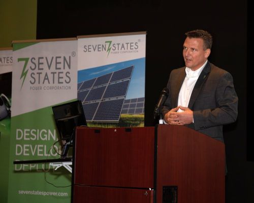 A man is standing at a podium giving a presentation for seven states