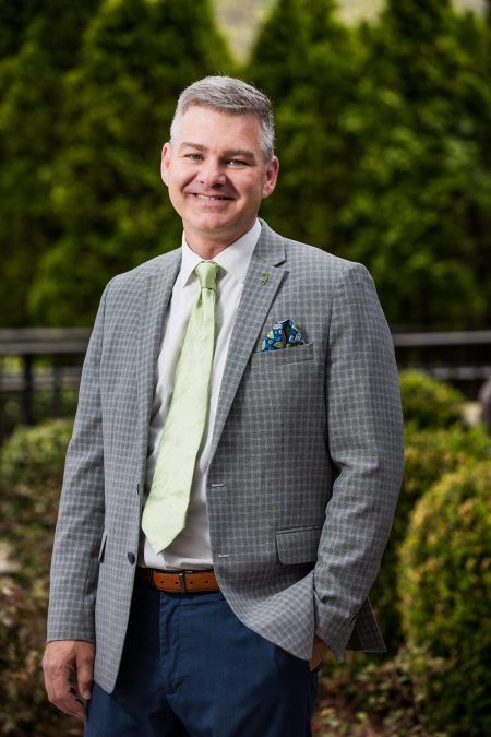 A man in a suit and tie is standing with his hands in his pockets.