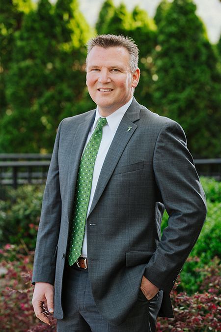 A man in a suit and tie is standing with his hands in his pockets.