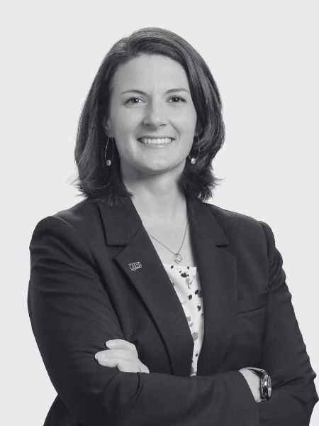 A black and white photo of a woman in a suit with her arms crossed