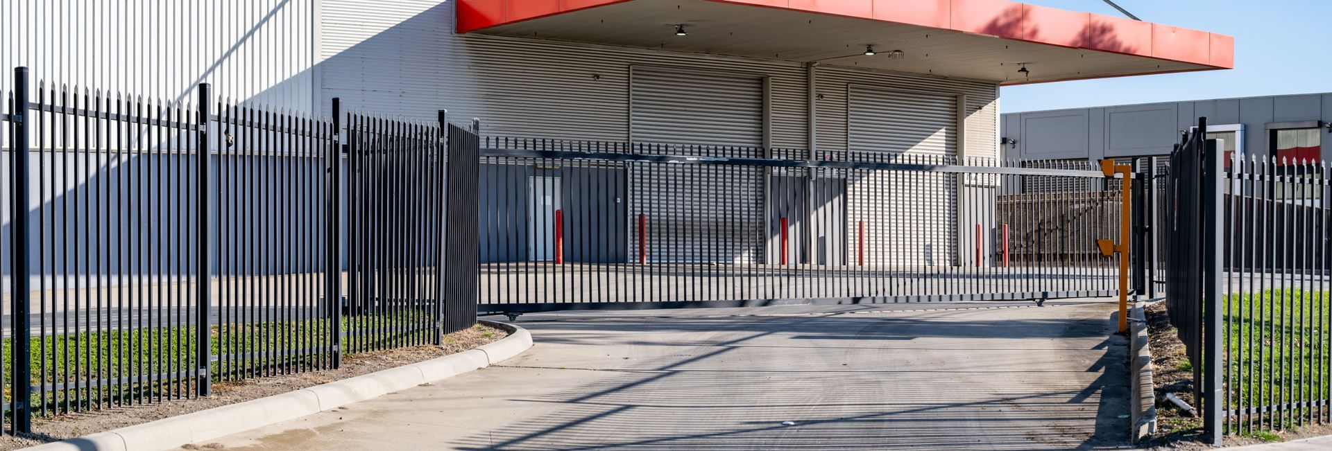 Secure industrial facility entrance with metal security fencing and an automated sliding gate.