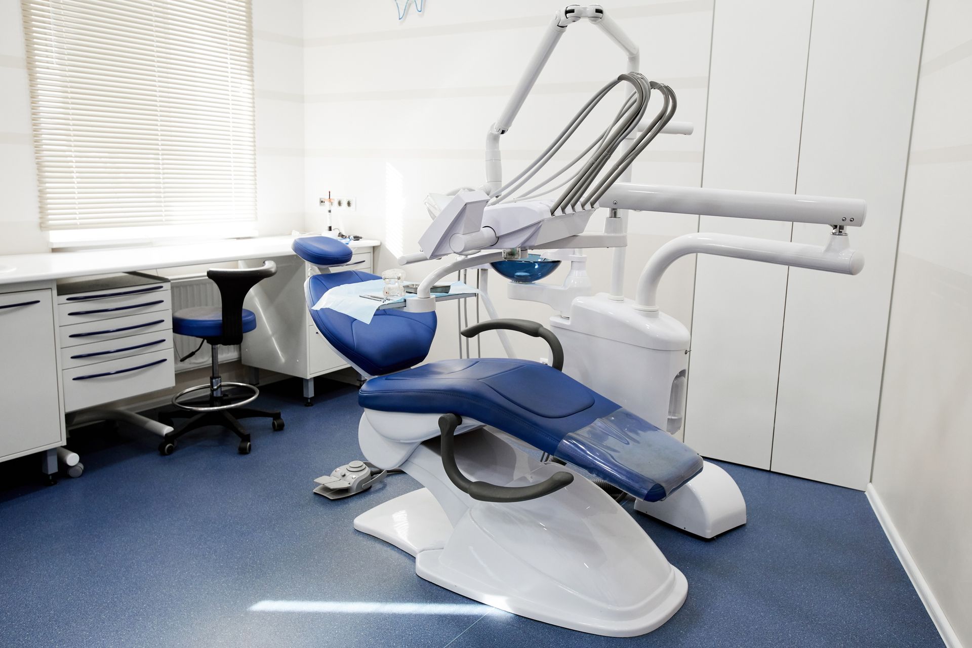 Wide angle background shot of a dental chair and equipment in an empty dentist's office.