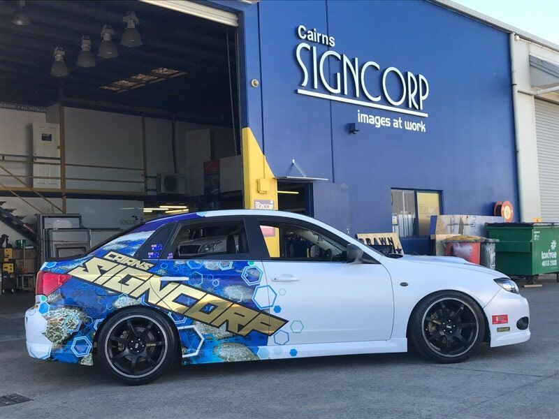 A White Car Is Parked In Front Of A Signcorp Building — Cairns Signcorp In Portsmith, QLD